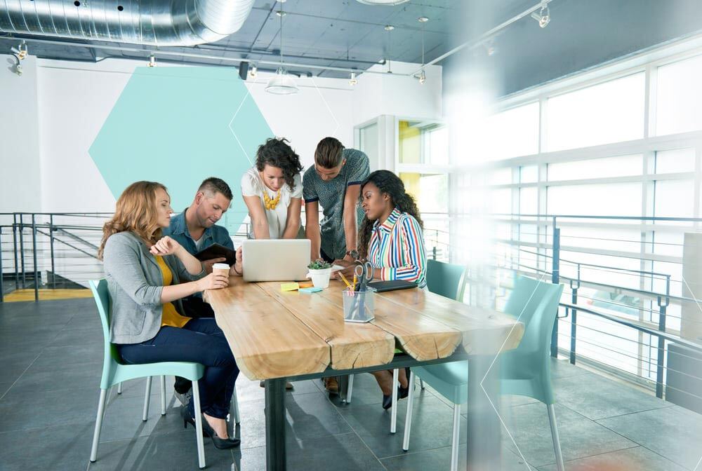 Multi-ethnic-group-of-succesful-creative-business-people-using-a-laptop-during-candid-meeting