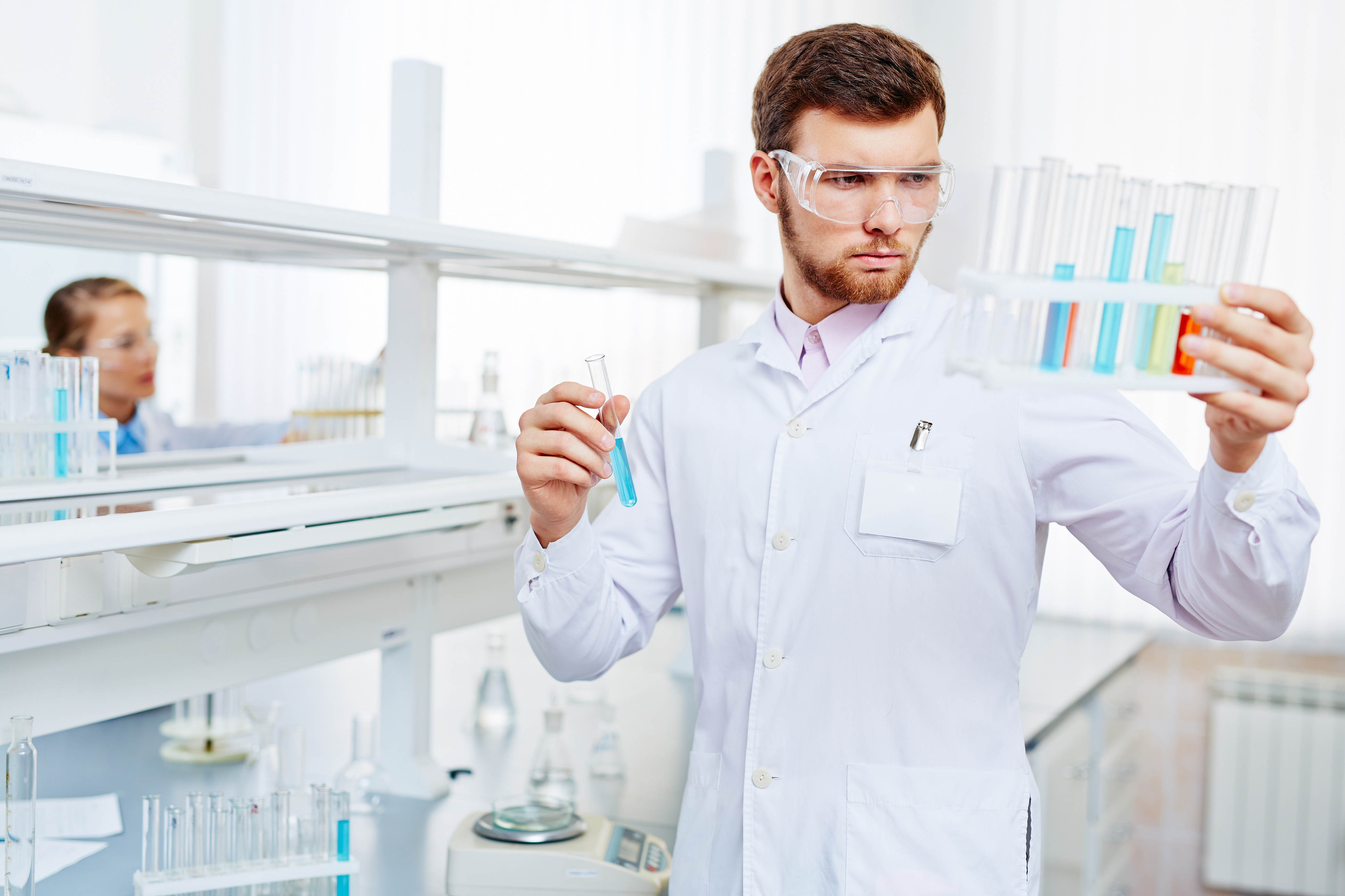 chemist observing flasks with chemical substances
